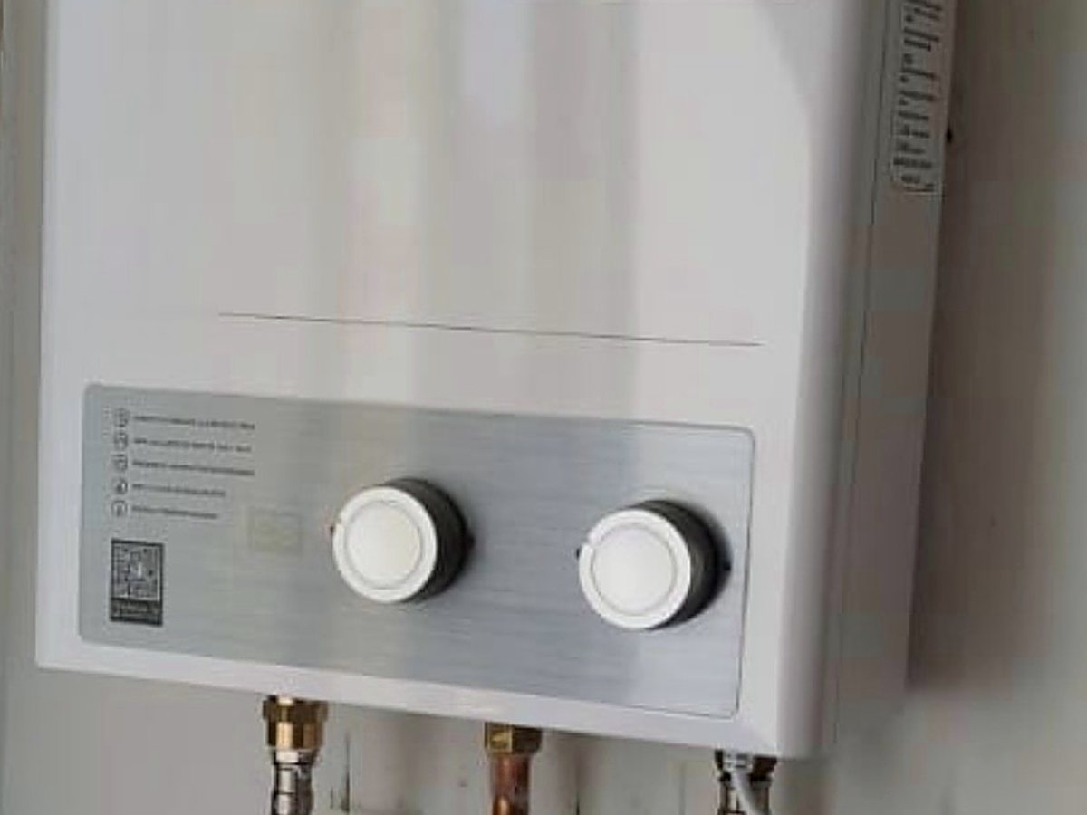 Calefón moderno instalado en el muro, con sus conexiones de gas y agua